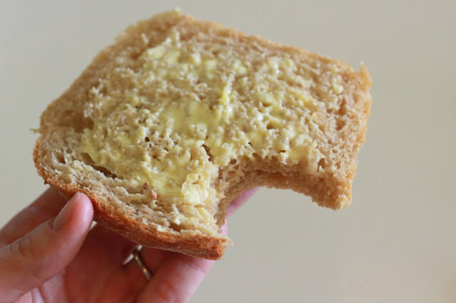 hand holding whole wheat bread with butter and bite taken out