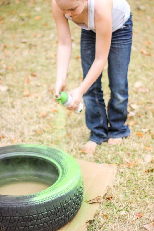 close up of a child spray painting a tire green