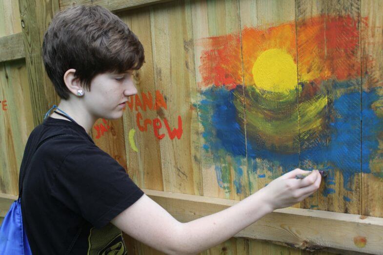 child painting a sunset on a fence