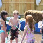 kids playing with a hose in a homemade pool