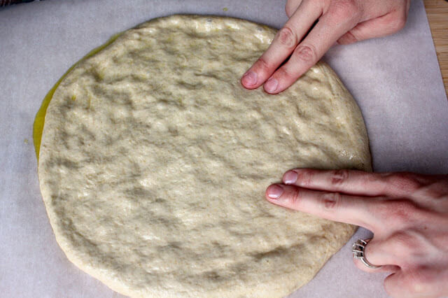 two hands pressing pizza dough