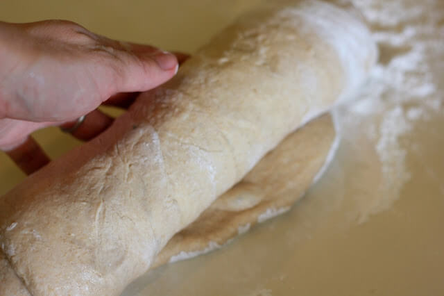 close shot of a hand rolling bread dough into a tube