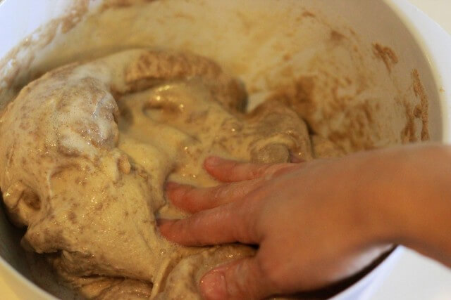 hand kneading bread dough with yeast mixture