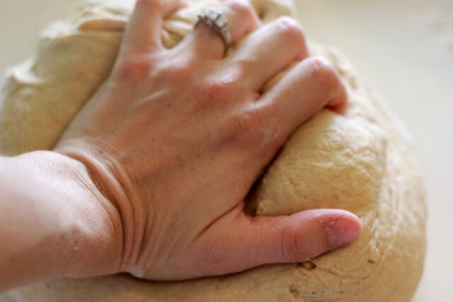 hand with wedding ring kneading bread dough