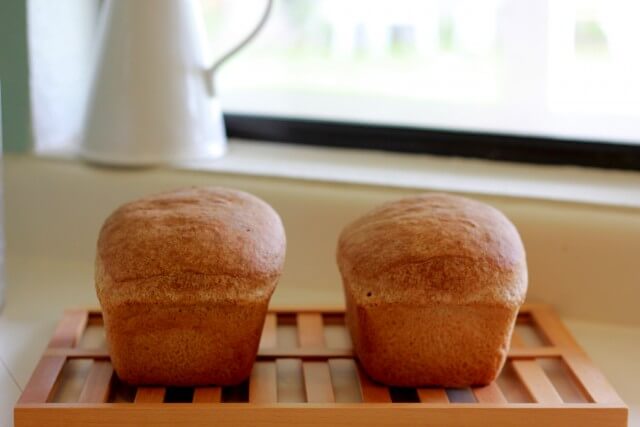 bread loaves resting on a wooden cooling rack