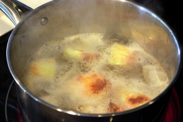 boiling pot with garlic cloves, onion, and cayenne pepper