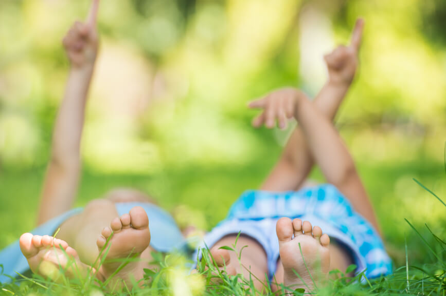 Group of happy children lying on green grass and pointing to the