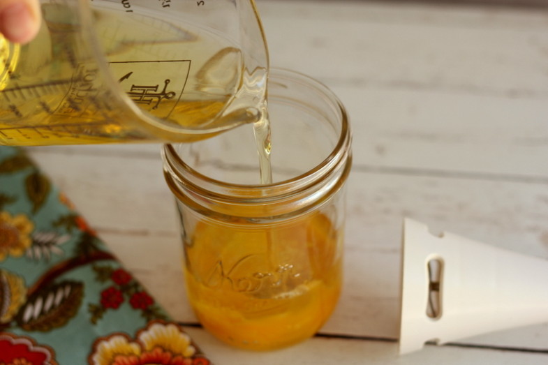 olive oil being poured into a glass jar