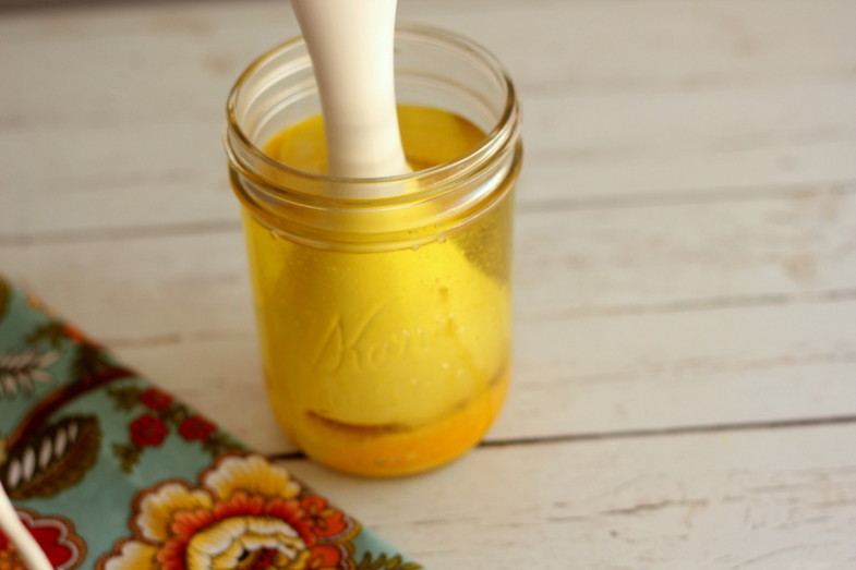 immersion blender mashing ingredients for homemade mayonnaise to the bottom of a glass jar