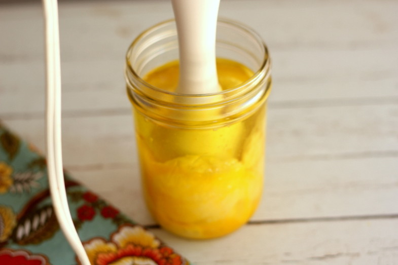 immersion blender mixing mayonnaise ingredients in a glass jar