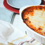 angled shot of zucchini lasagna on a painted white table with plates and cloth napkins