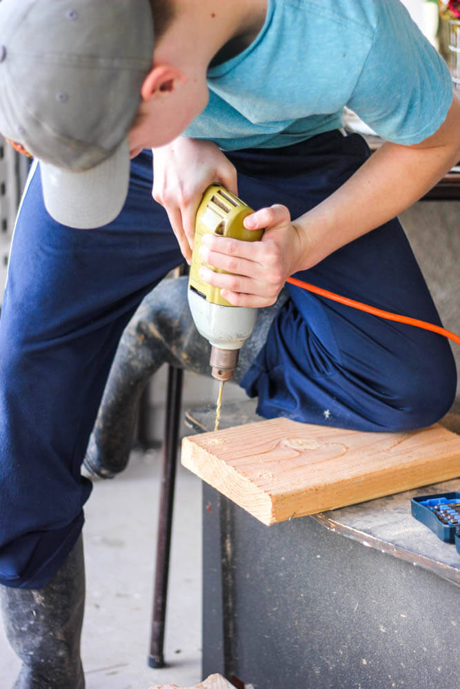 young boy drilling holes in a small board