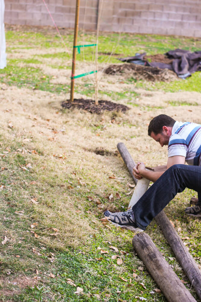 man twisting PVC pipe to dig a hole in a backyard