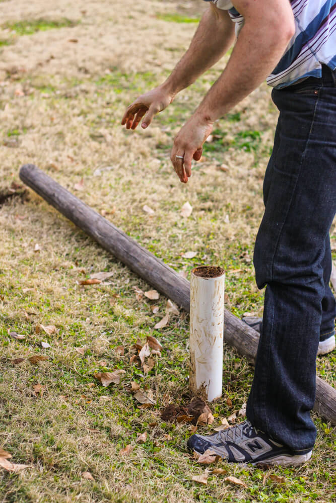 partial shot of man digging a hole with a PVC pipe