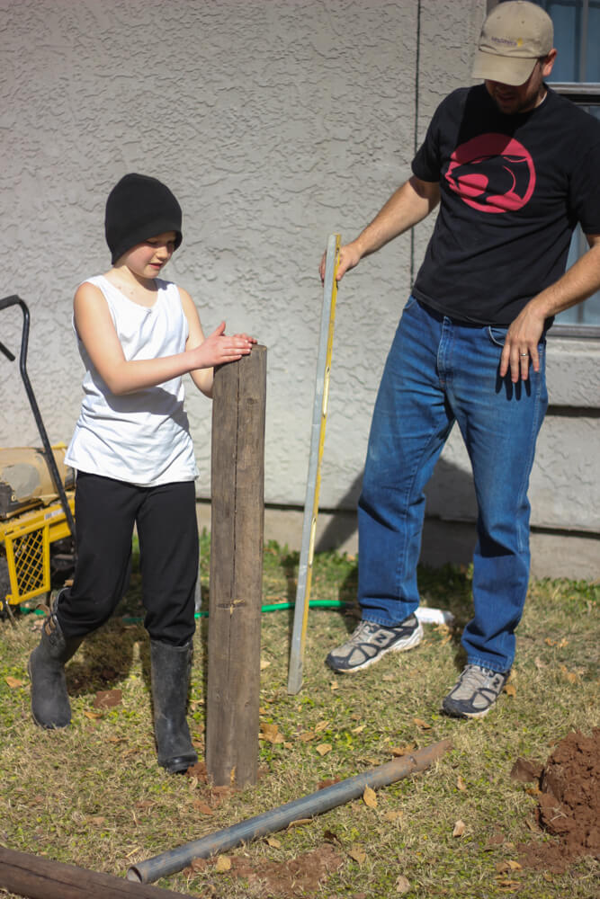 man and child leveling a post inserted in ground