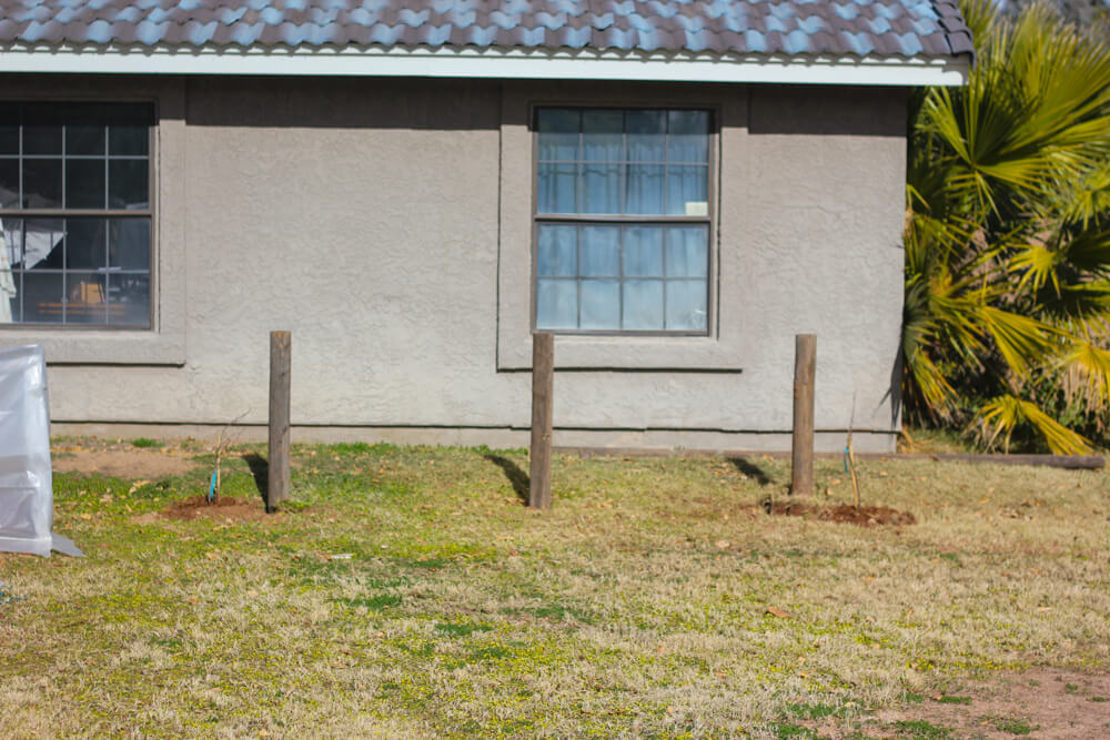 three posts standing in a backyard alongside a white house