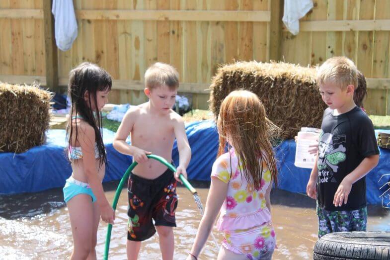 kids playing with a hose in a homemade pool