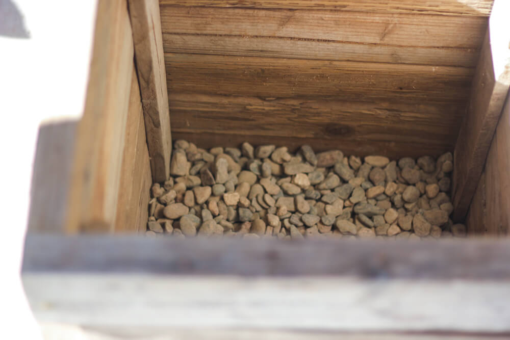 wooden planter with layer of river rocks at the bottom