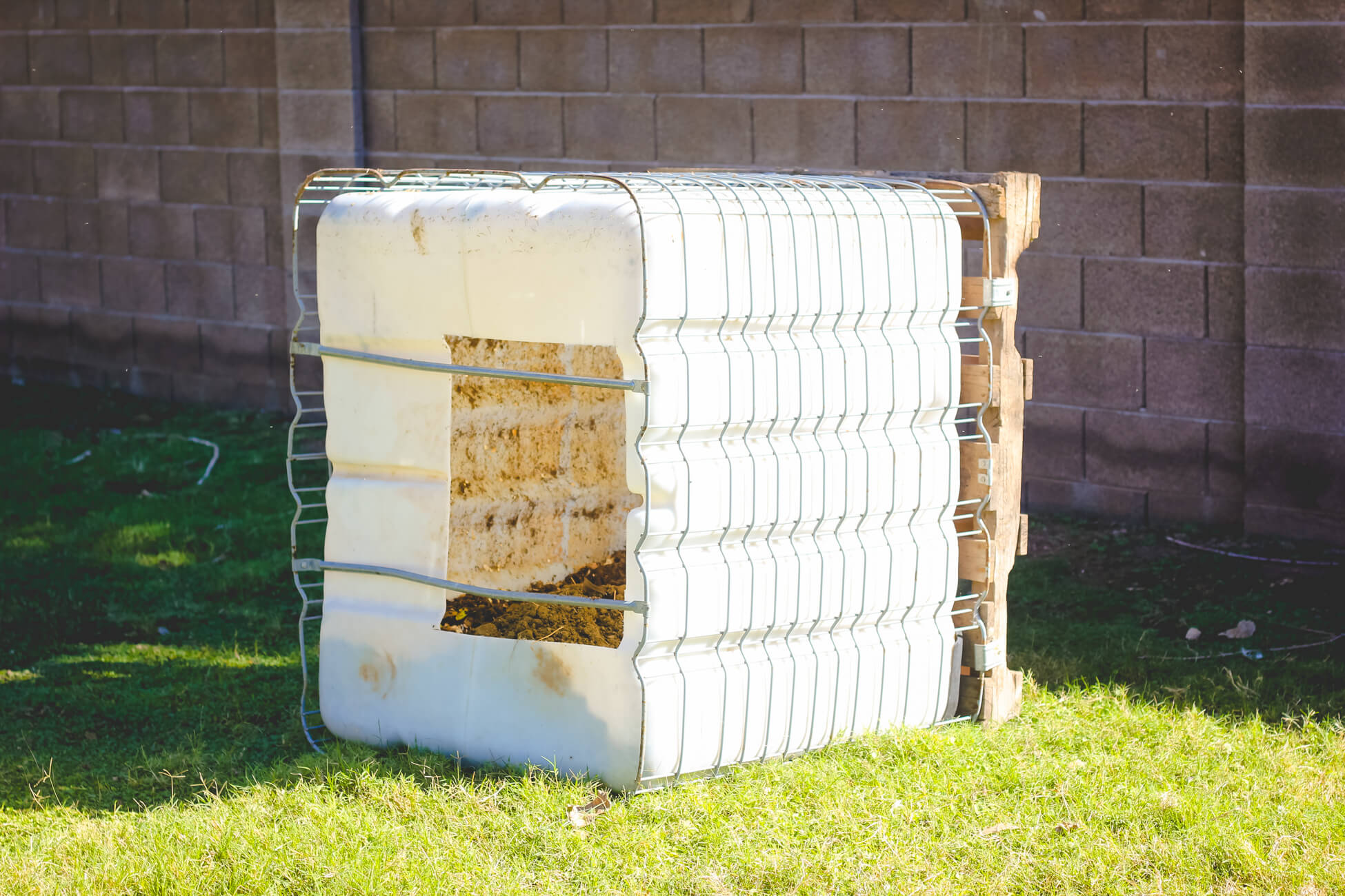 DIY compost bin on grass in yard.